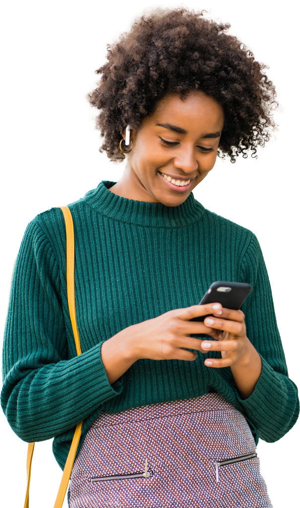 A woman wearing green with a yellow purse strap holding a phone and smiling at it